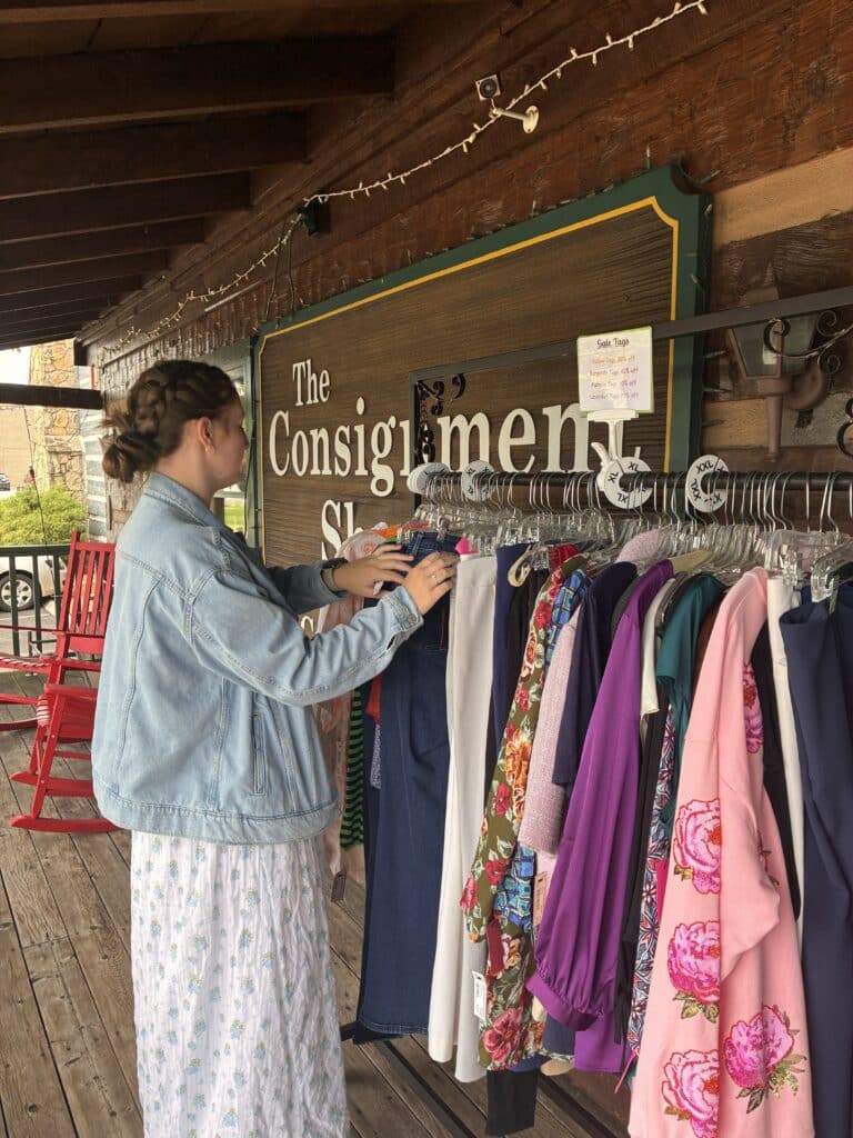 The Consignment Shoppe Clothes Shopping Thrift, woman shopping clothing rack besides exterior sign