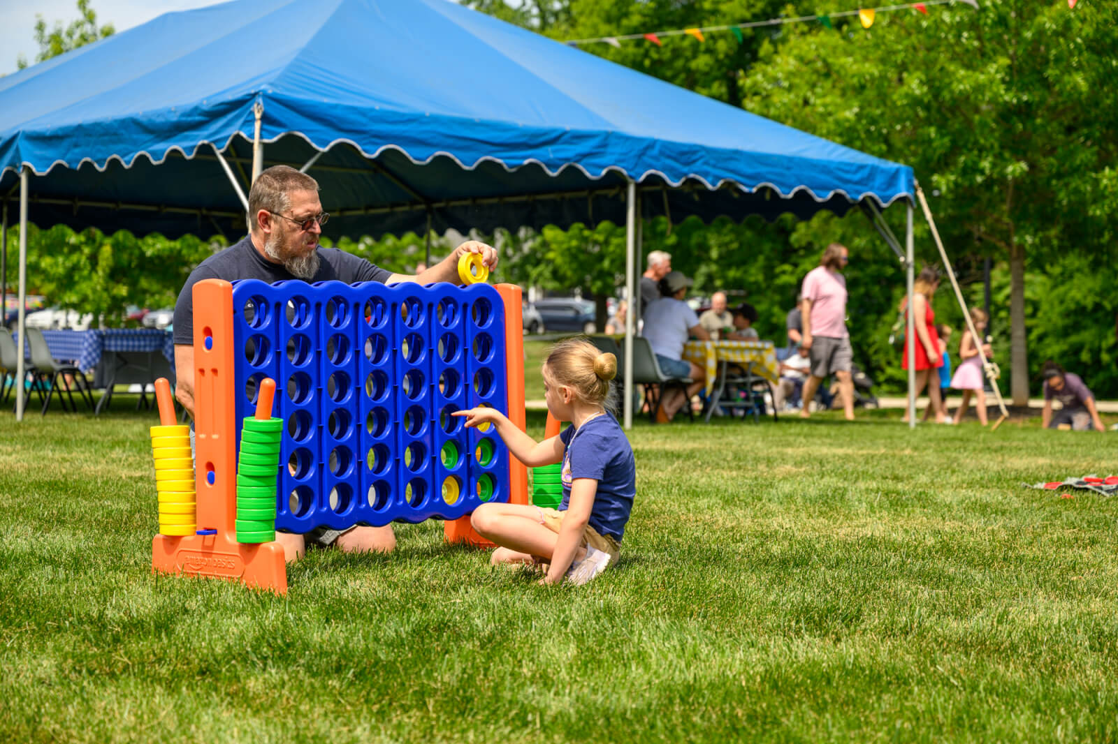 Father and daughter playing lawn game, connect four.