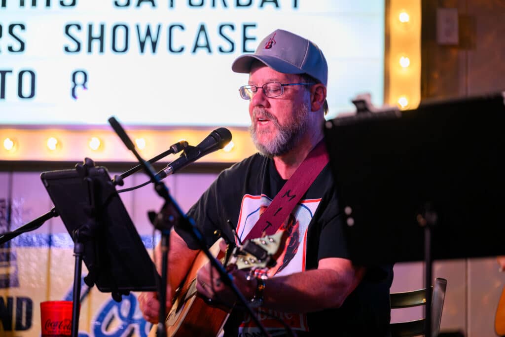 Man playing guitar and singing at Songwriter Showcase hosted at Wild Wings Cafe in Farragut