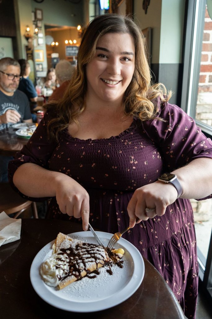 woman cutting into a sweet crepe