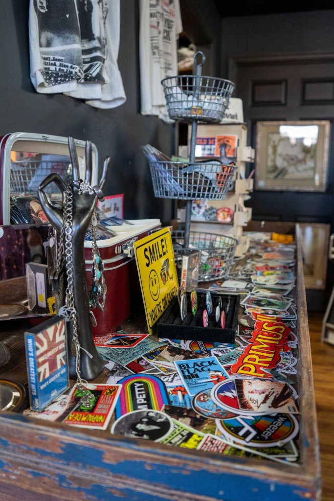 A menagerie of eclectic items including keychains, stickers, tshirts, rings, and other oddities on a table top