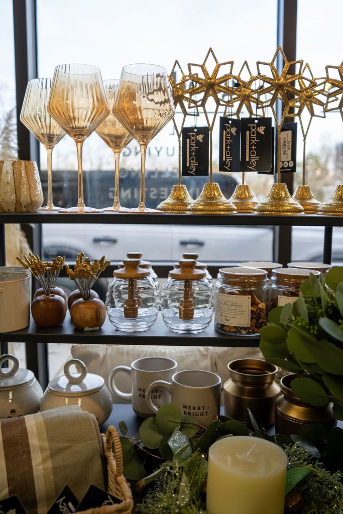 A decorative display of glasses, mugs, kitchen supplies, greenery, and various other home goods.